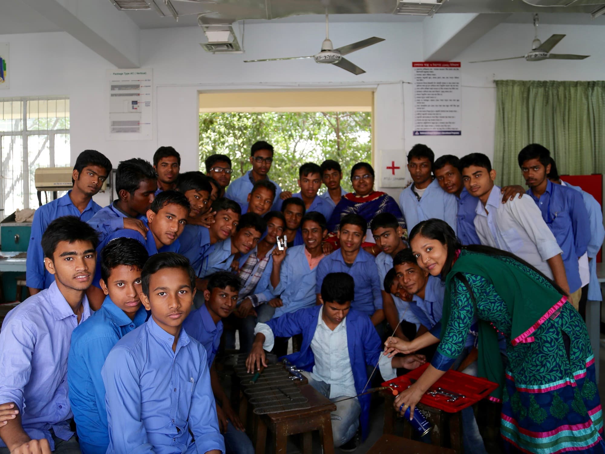 A large group of students in blue uniforms crowded together in a classroom