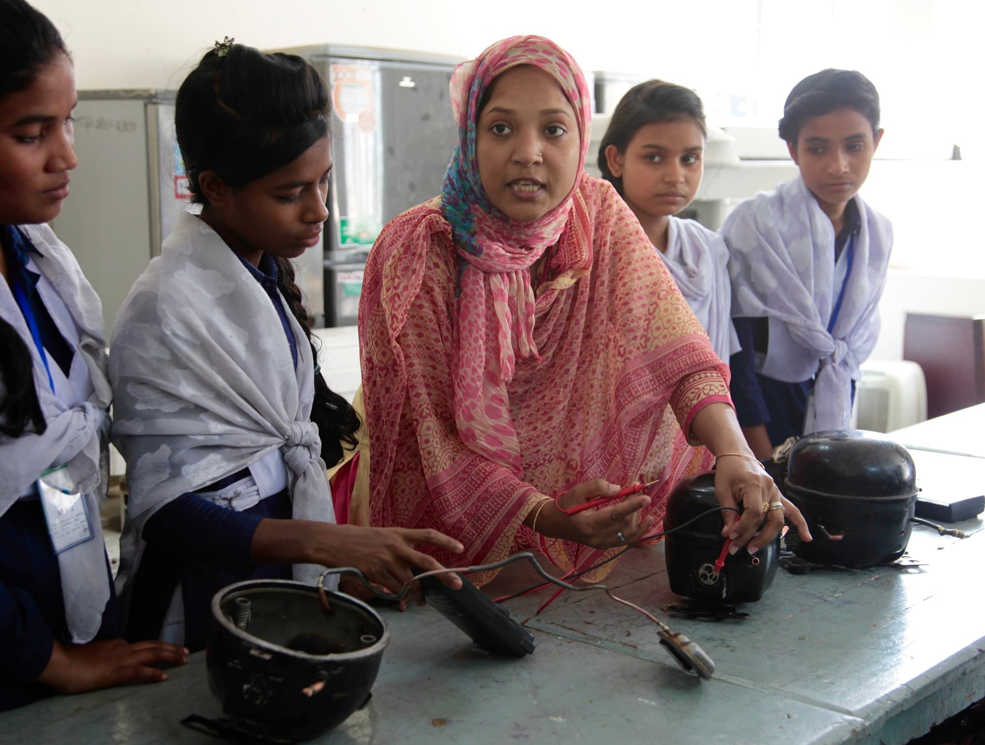 Students gathered around a bench working on equipment with their hands